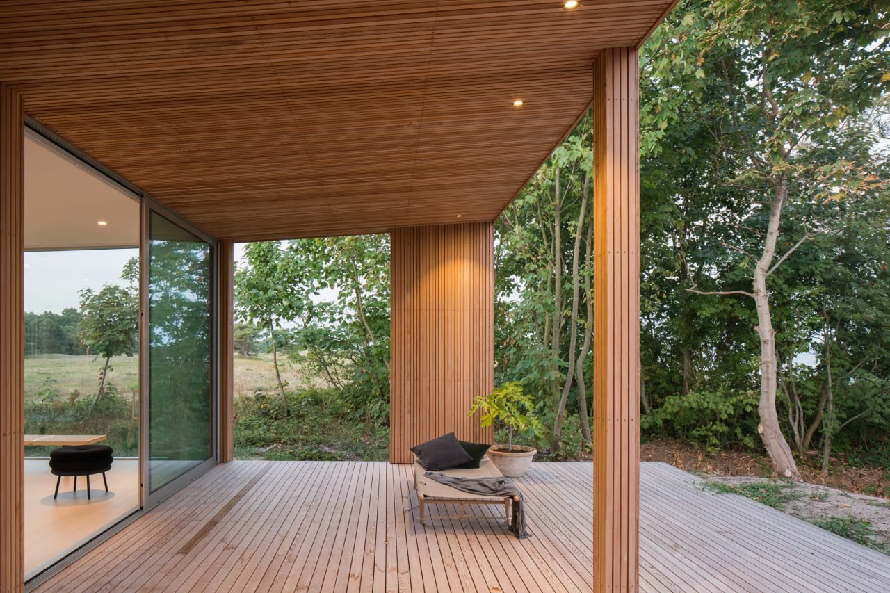 A wide lift-and-slide glass door standing open onto a winter garden, threshold flush with the floor